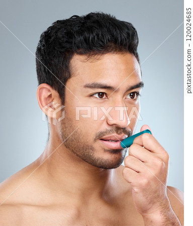 Skincare, lip balm and man with cosmetics, wellness and clear skin on grey studio background. Person, health and model with confidence, treatment and anti dry moisture with dermatology and grooming Skincare, lip balm and man with cosmetics, wellness and clear skin on grey studio background. Person, health and model with confidence, treatment and anti dry moisture with dermatology and grooming 120024685