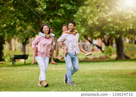 Family, park and walking with piggy back for wellness or happiness, together in nature for bonding. Mixed race people, children and parents on grass for vacation in Europe, smile for travel with kids 120024718