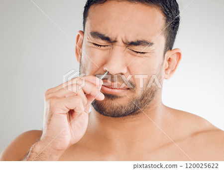 Man, nose and pain for hair removal, tweezers and dermatology for skincare in studio in morning. Asian male person, wellness and maintenance for face with epilation and tools by white background 120025622