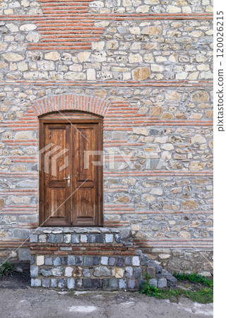 A stone building with a wooden double door and stone steps leading up to it. The door has a simple brass handle A stone building with a wooden double door and stone steps leading up to it. The door has a simple brass handle 120026215