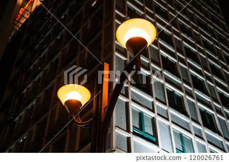 Orange, vintage street lights overlooking a tall building in Minsk at night. Orange, vintage street lights overlooking a tall building in Minsk at night. 120026761