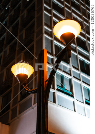 Orange, vintage street lights overlooking a tall building in Minsk at night. Orange, vintage street lights overlooking a tall building in Minsk at night. 120026763