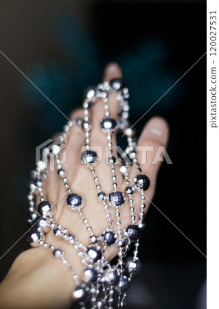 Woman holding silver beaded disco garland for christmas decoration. New Year 2025 Woman holding silver beaded disco garland for christmas decoration. New Year 2025 120027531