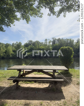 empty wooden picnic table in the park by river 120028237