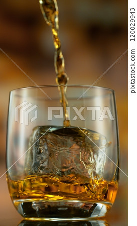 Freeze motion of pouring whisky into glass . Bar with bottles on background. 120029943
