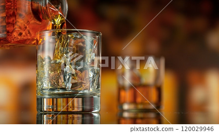 Freeze motion of pouring whisky into glass . Bar with bottles on background. Freeze motion of pouring whisky into glass . Bar with bottles on background. 120029946