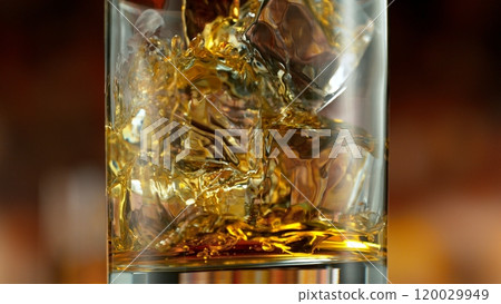 Freeze motion of pouring whisky into glass . Bar with bottles on background. 120029949