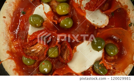 Super slow motion of falling fresh basil leaves on pizza dough with sugo, top down view 120029981
