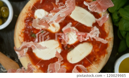 Super slow motion of falling fresh basil leaves on pizza dough with sugo, top down view Super slow motion of falling fresh basil leaves on pizza dough with sugo, top down view 120029985