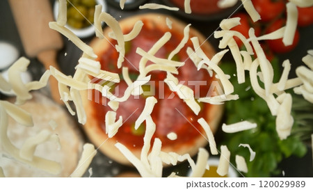 Super slow motion of falling fresh basil leaves on pizza dough with sugo, top down view 120029989