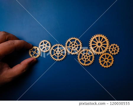 Hand holding wooden gear on a blue background. Business process and workflow automation. 120030555