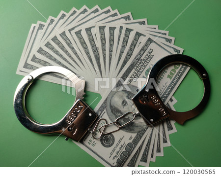 Top view banknotes and metal hand cuff on a green background. Top view banknotes and metal hand cuff on a green background. 120030565