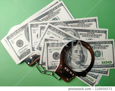 Top view banknotes and metal hand cuff on a green background. Top view banknotes and metal hand cuff on a green background. 120030572