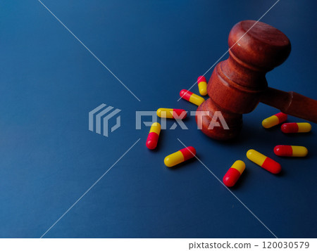 Closeup wooden gavel and medical pill on a blue background with copy space. 120030579