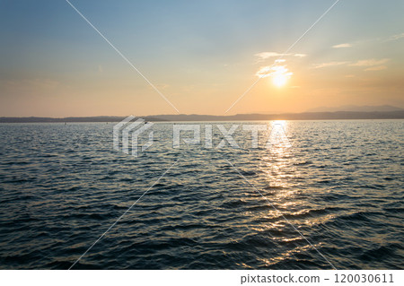 Beautiful purple sunset with floating boat on Lago di Garda near Scaliger Castle, Sirmione, Italy, romantic love concept 120030611