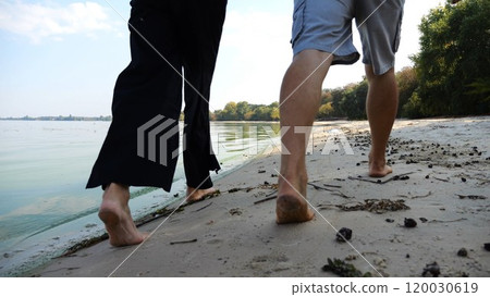 Bare feet of couple stepping together along beach at ocean background. Male and female legs of pair walking near sea. Happy lovers going on sandy shore. Concept of summer vacation or holiday. Bare feet of couple stepping together along beach at ocean background. Male and female legs of pair walking near sea. Happy lovers going on sandy shore. Concept of summer vacation or holiday. 120030619