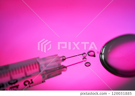 Injection syringe with a drop of drug on a rich pink background. Injection syringe with a drop of drug on a rich pink background. 120031885