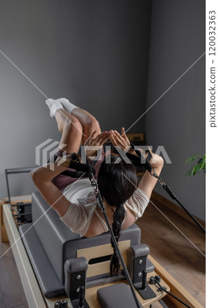 A woman is practicing Pilates on a reformer in a modern and welldesigned studio space 120032363
