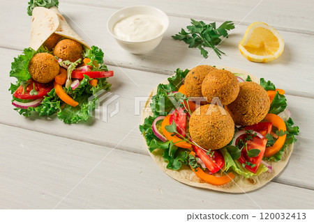 Tortillas, wrapped falafel balls, with fresh vegetables, vegetarian healthy food, on a wooden white background, no people, selective focus. Tortillas, wrapped falafel balls, with fresh vegetables, vegetarian healthy food, on a wooden white background, no people, selective focus. 120032413