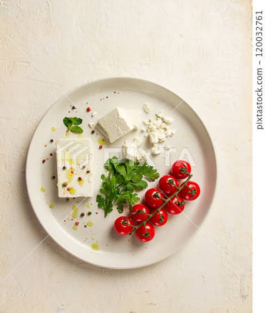feta cheese, for salads, with cherry , green butter, greens, on a white plate, appetizer, top view, close-up, 120032761