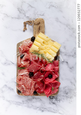 Assorted meat, appetizer, prosciutto, salami and ham, with maasdam cheese and olives, on a wooden board, breakfast, top view, close-up, no people 120032777