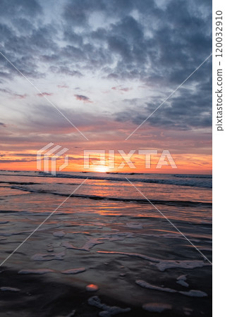 Beautiful Ocean Sunset with Dramatic Clouds reflecting on the Water, creating a serene scene 120032910