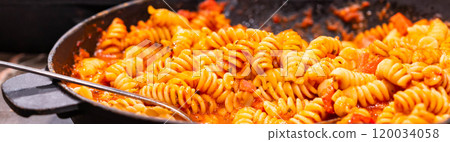 A close-up of delicious fusilli pasta tossed in rich tomato sauce, perfect for a hearty Italian meal experience. 120034058