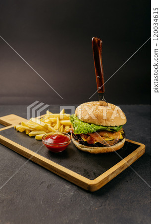 Classic burger with fresh lettuce and tomato served with crispy fries and ketchup on a wooden board Classic burger with fresh lettuce and tomato served with crispy fries and ketchup on a wooden board 120034615