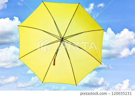 Open yellow umbrella on a blue background with white clouds Open yellow umbrella on a blue background with white clouds 120035231