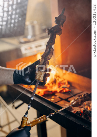 Close-up of skewered meat roasting over an open flame, capturing intense heat and flavor of grilling 120035418