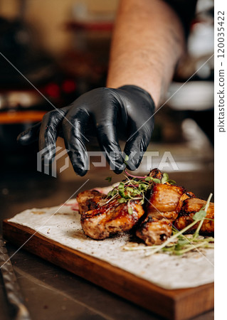 Chef garnishing grilled ribs with fresh greens, adding the final touch to a savory dish 120035422