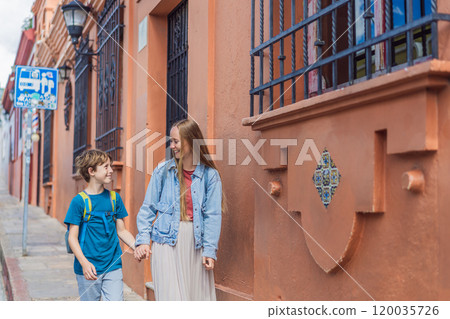 Mother and her son tourists walks through the colonial streets San Cristobal de las Casas, Mexico. Cultural exploration, architecture, and travel experience concept 120035726