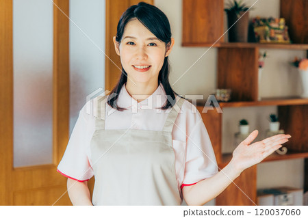 A young caregiver in an apron at a nursing facility A young caregiver in an apron at a nursing facility 120037060