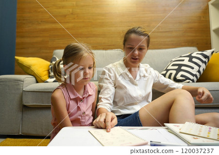 A mother supports her daughter with homework 120037237