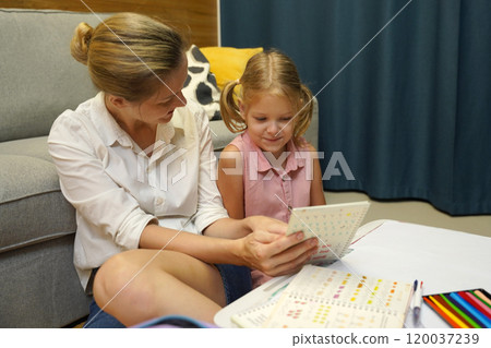 A mother supports her daughter with homework 120037239