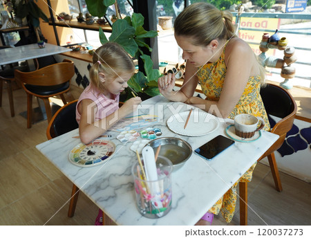 A young mother and her daughter enjoy a creative art session at home  120037273