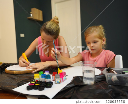 A mother and her young daughter engage in a colorful painting activity  120037558