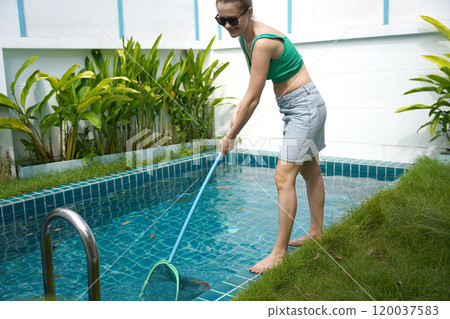 A young woman clean leaves out of a pool A young woman clean leaves out of a pool 120037583