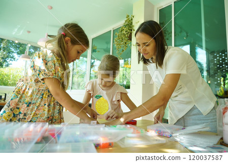Teacher in workshop teched two girls how to assemble a thermo mosaic  120037587
