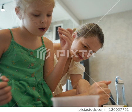 Mother and her daughter paint Halloween cookies  120037761
