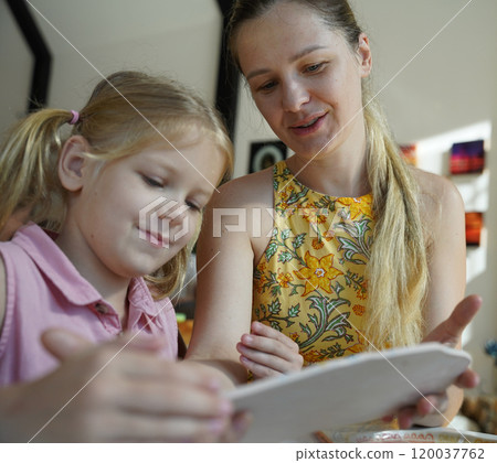 A young mother and her daughter enjoy a creative art session at home  120037762