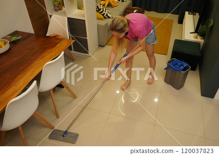 A woman is cleaning her living room at home A woman is cleaning her living room at home 120037823
