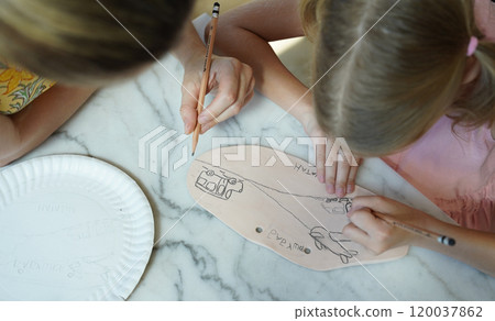 A young mother and her daughter enjoy a creative art session at home  120037862