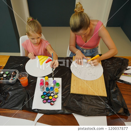 A mother and her young daughter engage in a colorful painting activity  120037877