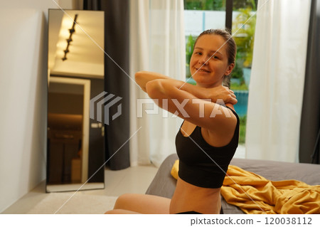 A young woman is enjoying a wonderfully serene morning in her bedroomnd  120038112
