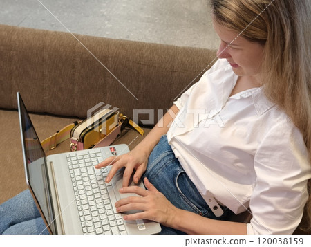 A young woman enjoys coffee while working on her laptop A young woman enjoys coffee while working on her laptop 120038159