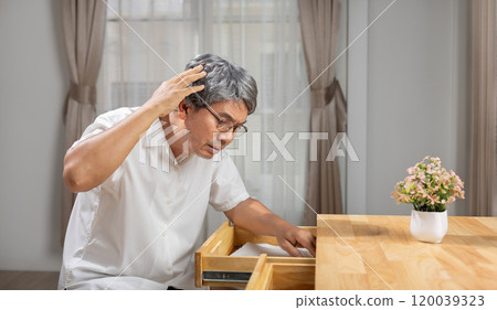 Asian older man finding something that he forgot it in drawers. Asian older man finding something that he forgot it in drawers. 120039323