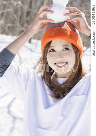 A young woman with a small snowman on her head at a ski resort - Ski/snowboard image 120041962