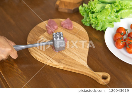 person beats meat with a meat tenderizer 120043619