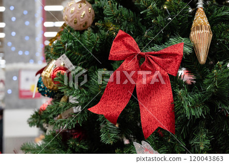 Christmas tree decorations featuring a red bow and ornaments. 120043863